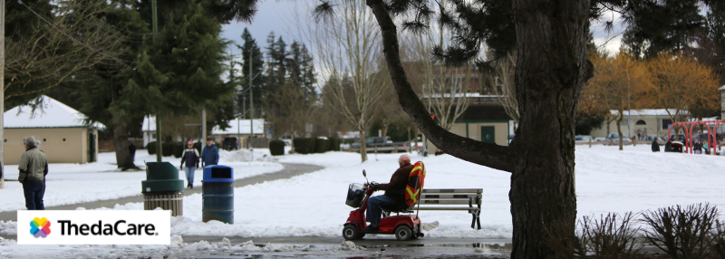 Man on mobility scooter outside in the winter with snow on the ground around him