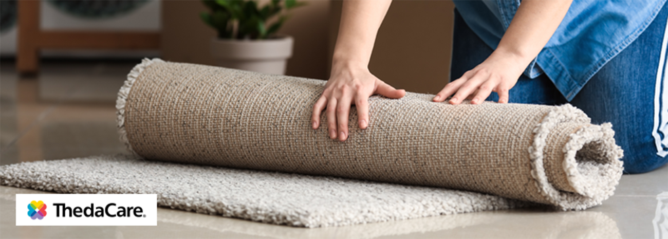 A woman rolling up a rug