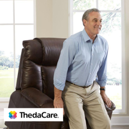Image shows smiling older man standing up from lift chair in indoor setting
