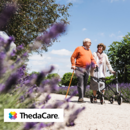Senior couple out on a walk by lavender plants with man using cane and woman using rollator