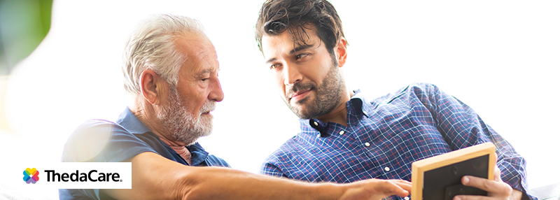 Adult man looking at a photo with his elderly father