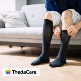 Man sitting on couch and pulling on black compression stockings