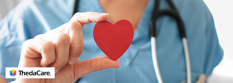 Healthcare professional wearing stethoscope holding a small red heart 