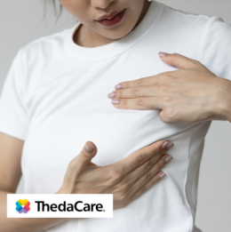 Woman with hand on her chest, performing a breast check