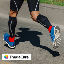 Athlete running outside with black compression socks on and blue running shoes