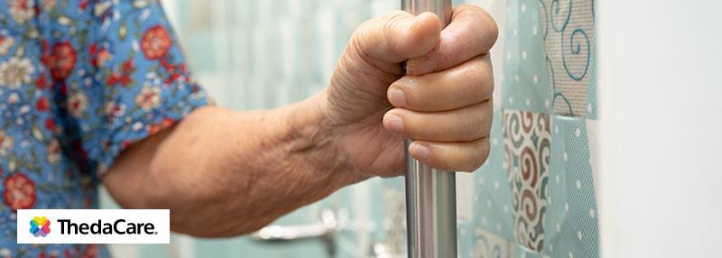 Older woman's hand holding onto grab bar in bathroom