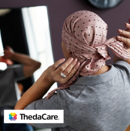 Woman who is recovering from breast cancer surgery tying a head wrap 