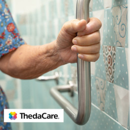 Older woman's hand holding onto grab bar in bathroom