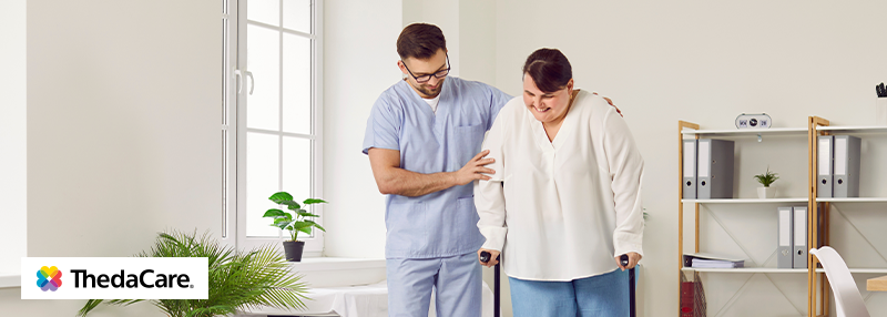 Heavier set woman walking with crutches with doctor's assistance